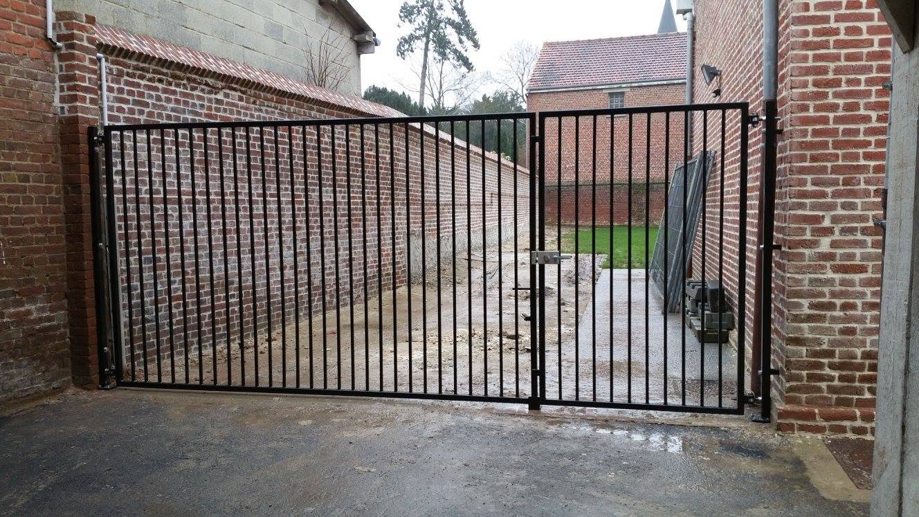 Portail métallique à barreaux droits installé entre deux murs en brique